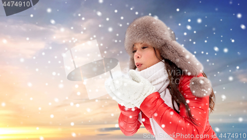 Image of happy woman with snow in winter fur hat outdoors