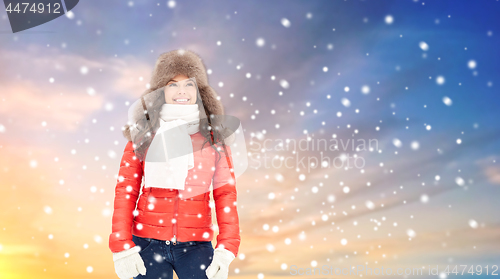 Image of happy woman in winter fur hat over sky and snow