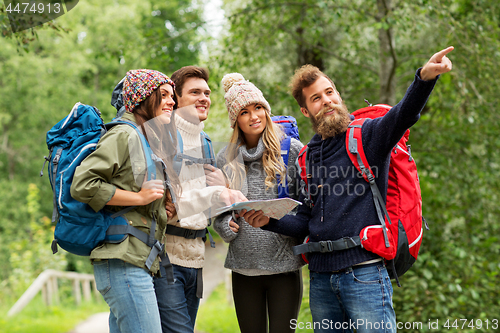 Image of friends or travelers hiking with backpacks and map