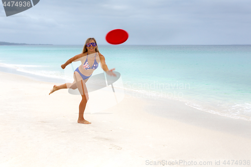 Image of Vivacious Australian girl playing frisbee idyllic beach paradise