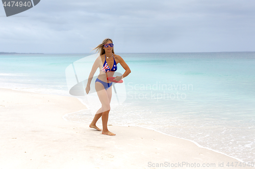 Image of Aussie girl playing frisbee on idyllic beach. Beach culture, fitness