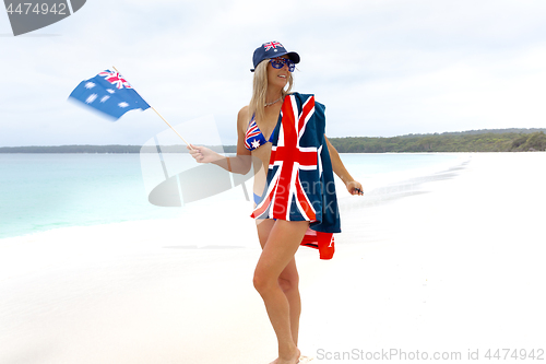 Image of Aussie girl waving Australian flag on stunning pristine beach