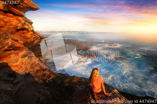 Image of Female on rocks watching the ocean cascade around coastal rocks