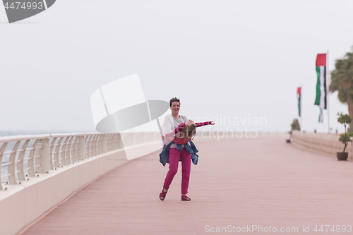 Image of mother and cute little girl on the promenade by the sea