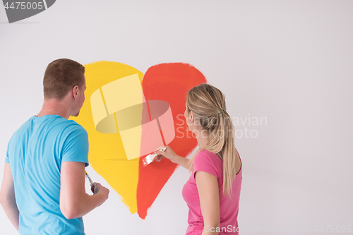 Image of couple are painting a heart on the wall