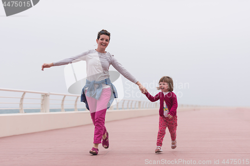 Image of mother and cute little girl on the promenade by the sea