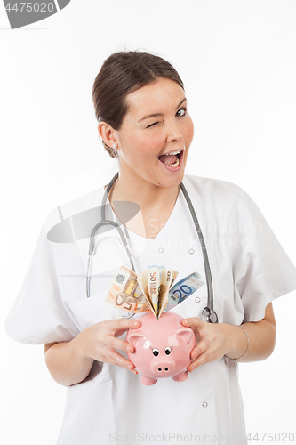 Image of happy woman doctor with piggy bank full of money