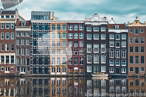 Image of houses and boat on Amsterdam canal Damrak with reflection. Ams