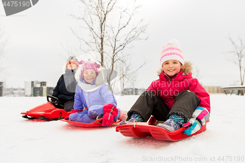 Image of happy little kids sliding on sleds in winter