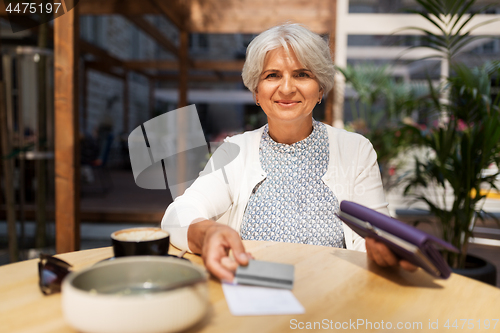 Image of senior woman with credit card paying bill at cafe