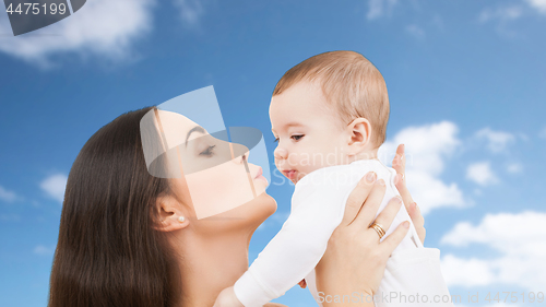 Image of mother kissing baby over sky background