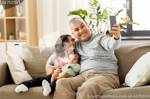 Image of happy father with sons taking selfie at home