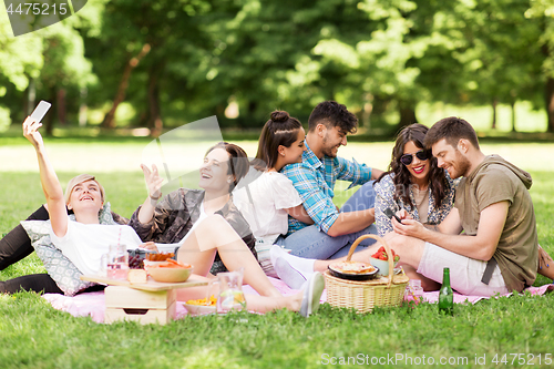 Image of friends with smartphones on picnic at summer park