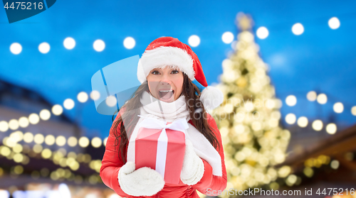 Image of happy woman with gift over christmas tree