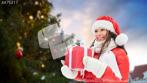 Image of happy woman with gift over christmas tree