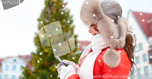 Image of woman with smartphone over christmas tree