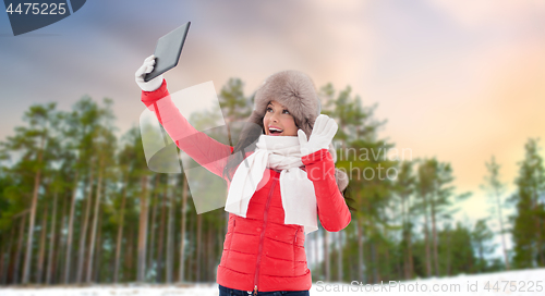 Image of woman in winter fur hat with tablet pc outdoors