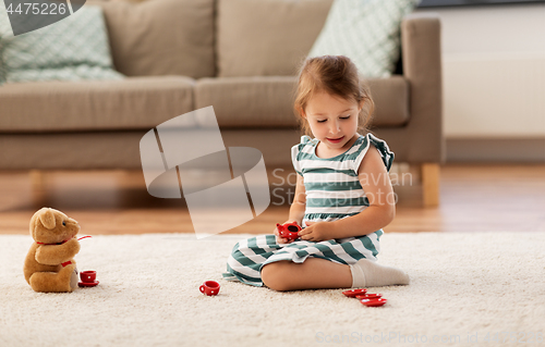 Image of little girl playing with toy tea set at home