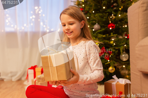 Image of smiling girl with christmas gift at home