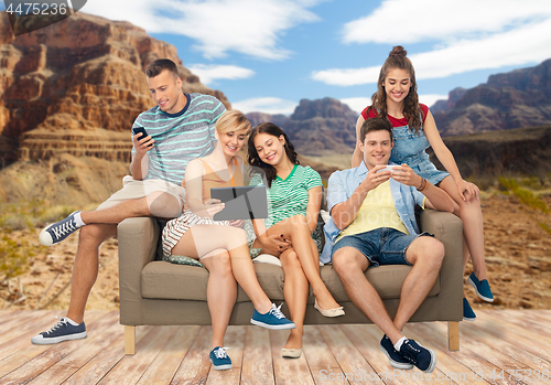 Image of friends with tablet pc and smartphones sit on sofa