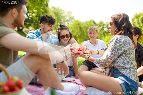 Image of happy friends sharing watermelon at summer picnic