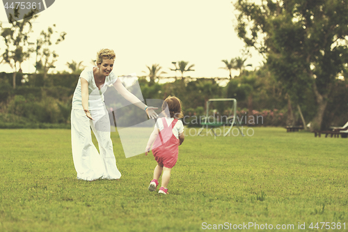 Image of mother and little daughter playing at backyard