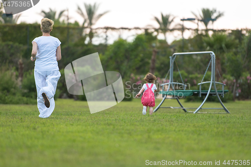 Image of mother and little daughter playing at backyard