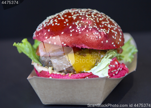Image of Red burger sprinkled with sesame seeds on a street market