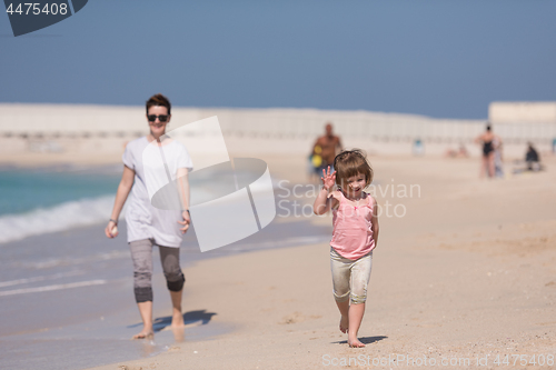 Image of mother and daughter running on the beach