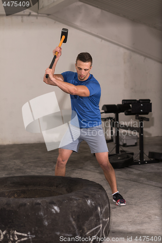 Image of man workout with hammer and tractor tire