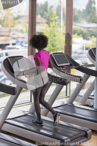 Image of afro american woman running on a treadmill