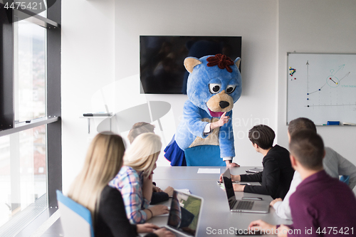 Image of boss dresed as bear having fun with business people in trendy of