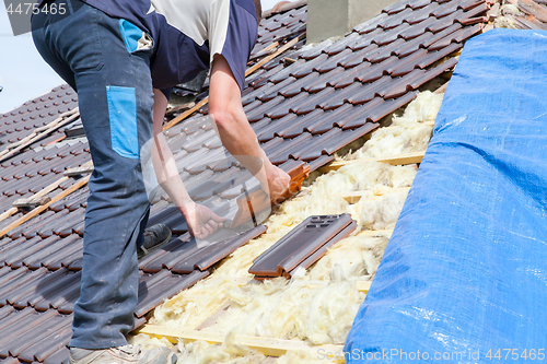 Image of a roofer laying tile on the roof