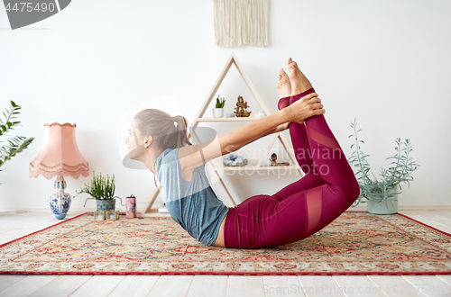 Image of young woman doing bow pose at yoga studio