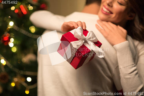 Image of close up of couple with christmas gift hugging