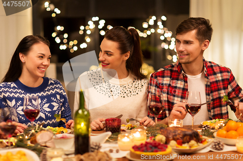 Image of happy friends having christmas dinner at home