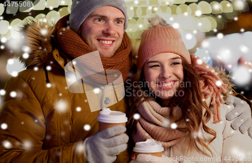 Image of happy couple with coffee over christmas lights