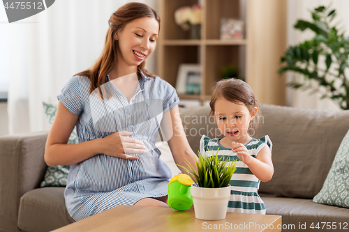 Image of pregnant mother and daughter with home plant