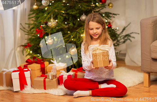 Image of smiling girl with christmas gift at home