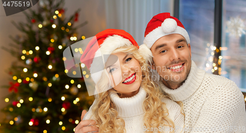 Image of couple in santa hats over christmas tree lights