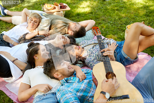 Image of friends playing guitar and chilling at summer park