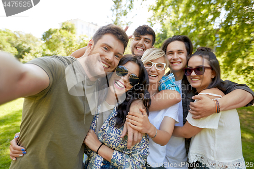 Image of happy friends taking selfie outdoors in summer