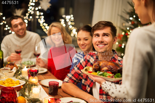 Image of happy friends having christmas dinner at home