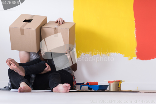 Image of young multiethnic couple playing with cardboard boxes