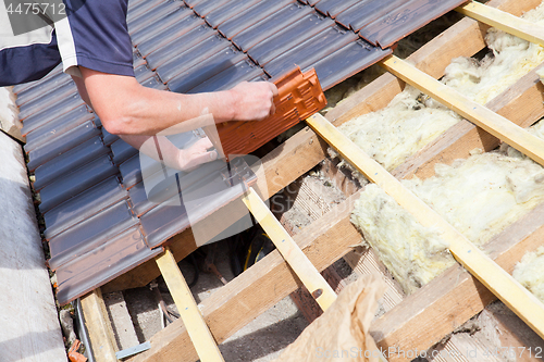 Image of a roofer laying tile on the roof