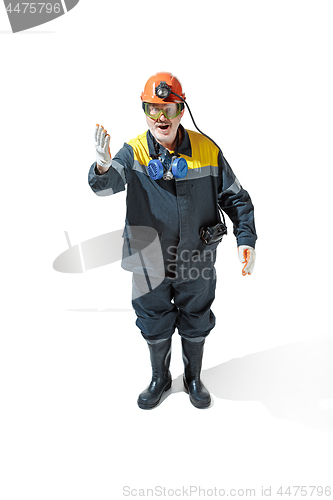 Image of The studio shot of senior bearded male miner standing at the camera on a white background.