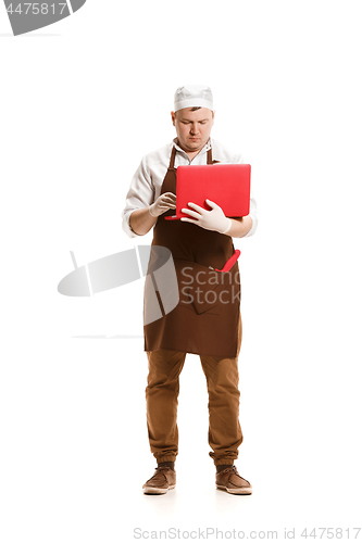 Image of Serious butcher posing with a laptop isolated on white background