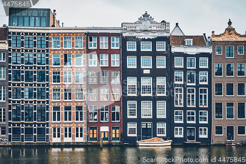 Image of houses and boat on Amsterdam canal Damrak with reflection. Ams