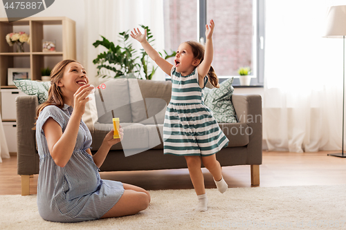 Image of pregnant mother and daughter blowing soap bubbles