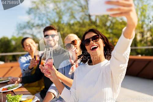 Image of happy friends taking selfie at rooftop party